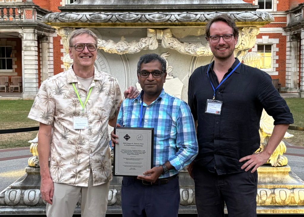 Gopal Pandurangan, center, with collaborators Roger Wattenhofer, left, and Stephan Holzer at the ACM Symposium on Principles of Distributed Computing (PODC) 2026 conference in London, where Pandurangan received the Edsger W. Dijkstra Prize in Distributed Computing.