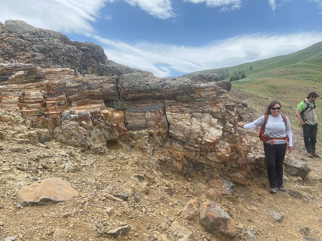 Professor Jennifer Lindline standing next to a petrified tree stump. Photo credit: Jack McLaughlin, TA