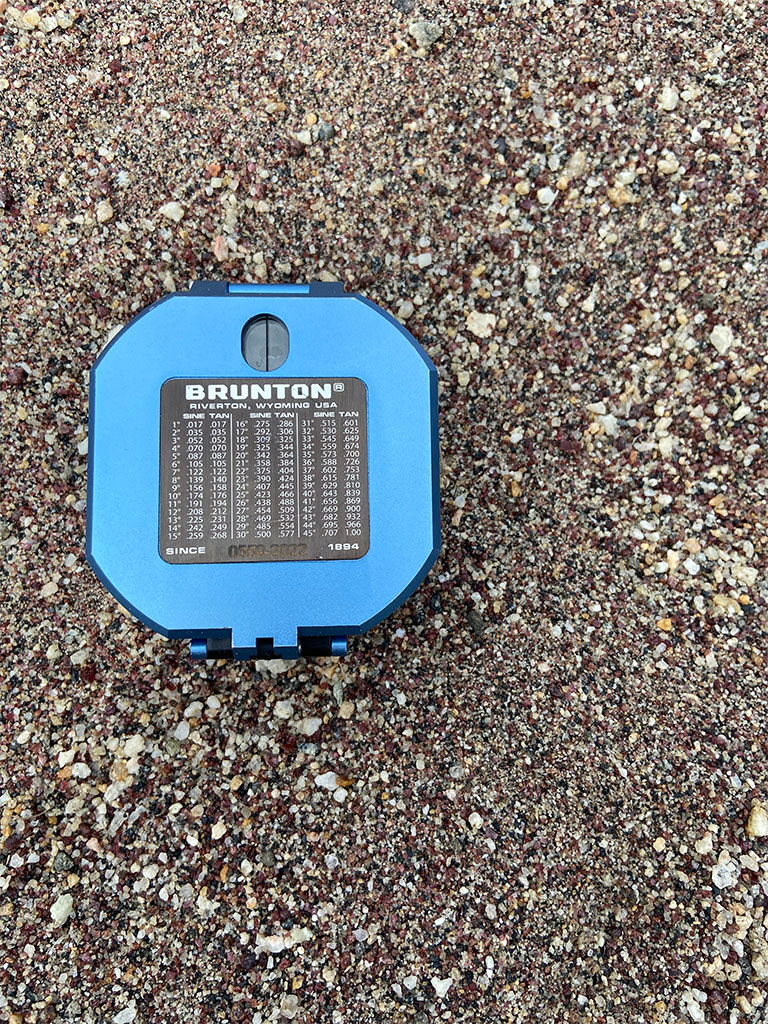 The red minerals are all fragments of garnet. Brunton for scale. Photo credit: Jack McLaughlin, TA