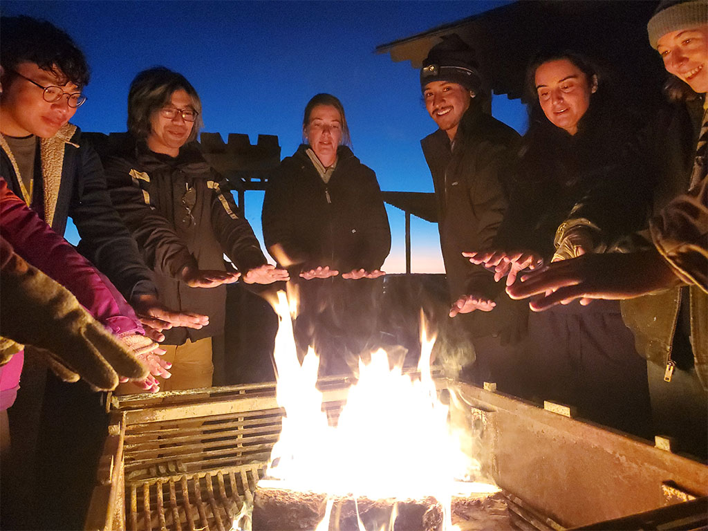 Everyone gathered around the fire on s’mores night, warming their hands and enjoying a well-deserved break together. Photo credit: Noam Mullinax