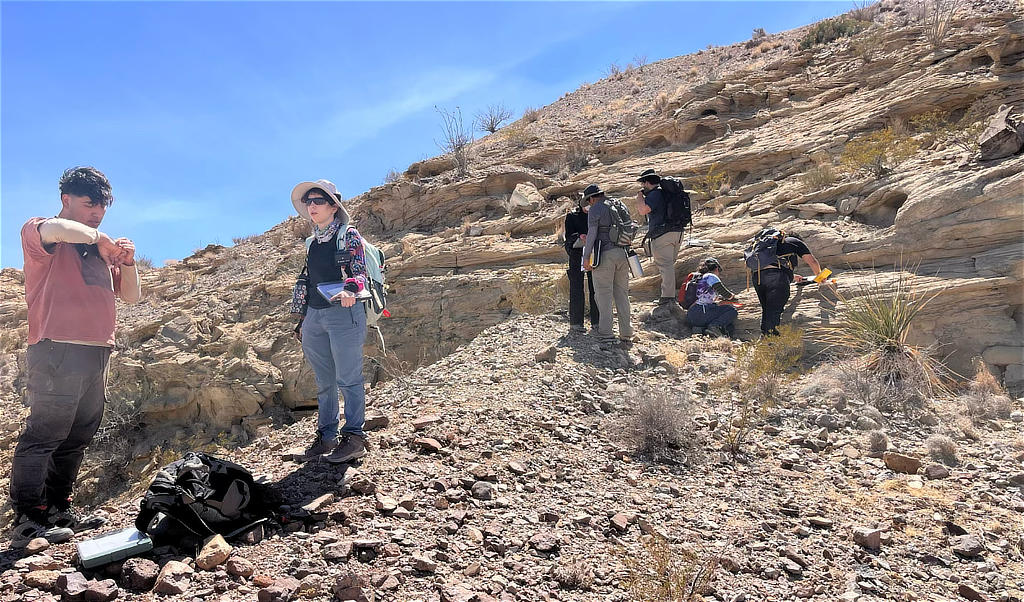Students Emilio Gomez and Michelle Lecompte unpack for a lunch break while another group takes measurements of a nearby outcrop.