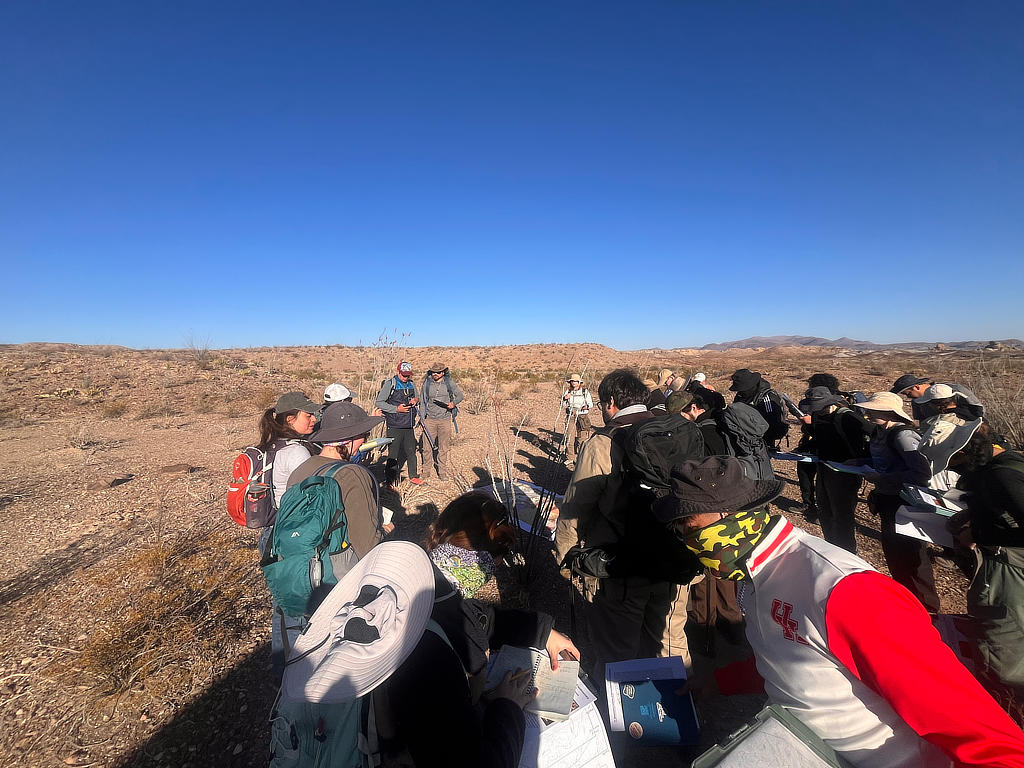 Photo Credit: TA Abe Okayli-Masryk - Students gather around Dr. Mike Murphy and teaching assistant Michael Daniel for a field safety moment and to get an introduction to the geologic units of the Tornillo Flats mapping area in Big Bend National Park.