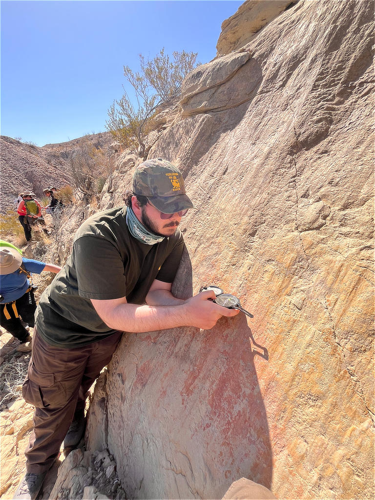 Photo Credit: TA Abe Okayli-Masryk - Student Tariq El Awawdeh demonstrating flawless technique in measuring the attitude of the strike and the dip of this textbook example of a normal fault surface that preserves the motion via grooves, chatter marks, and slickenlines.