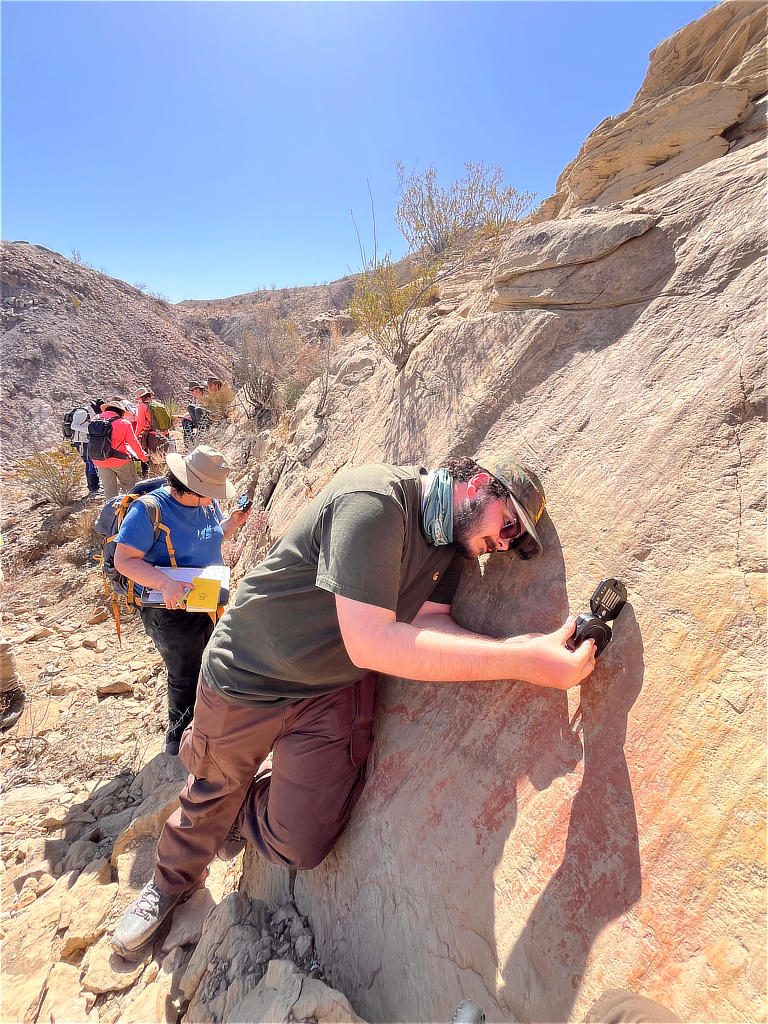 Photo Credit: TA Abe Okayli-Masryk - Student Tariq El Awawdeh demonstrating flawless technique in measuring the attitude of the strike and the dip of this textbook example of a normal fault surface that preserves the motion via grooves, chatter marks, and slickenlines.
