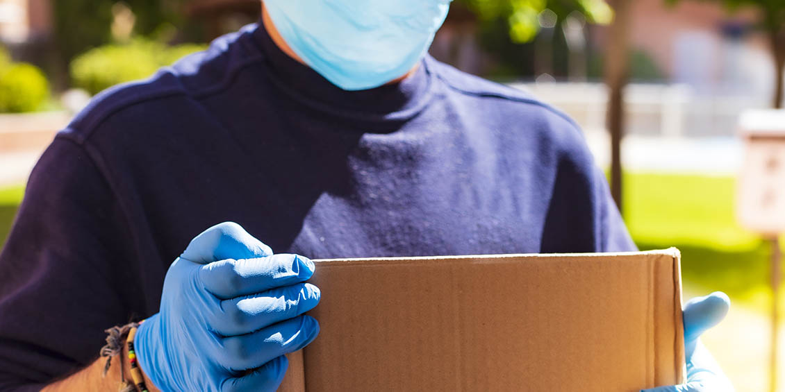 stock photo of gloved, masked person carrying box