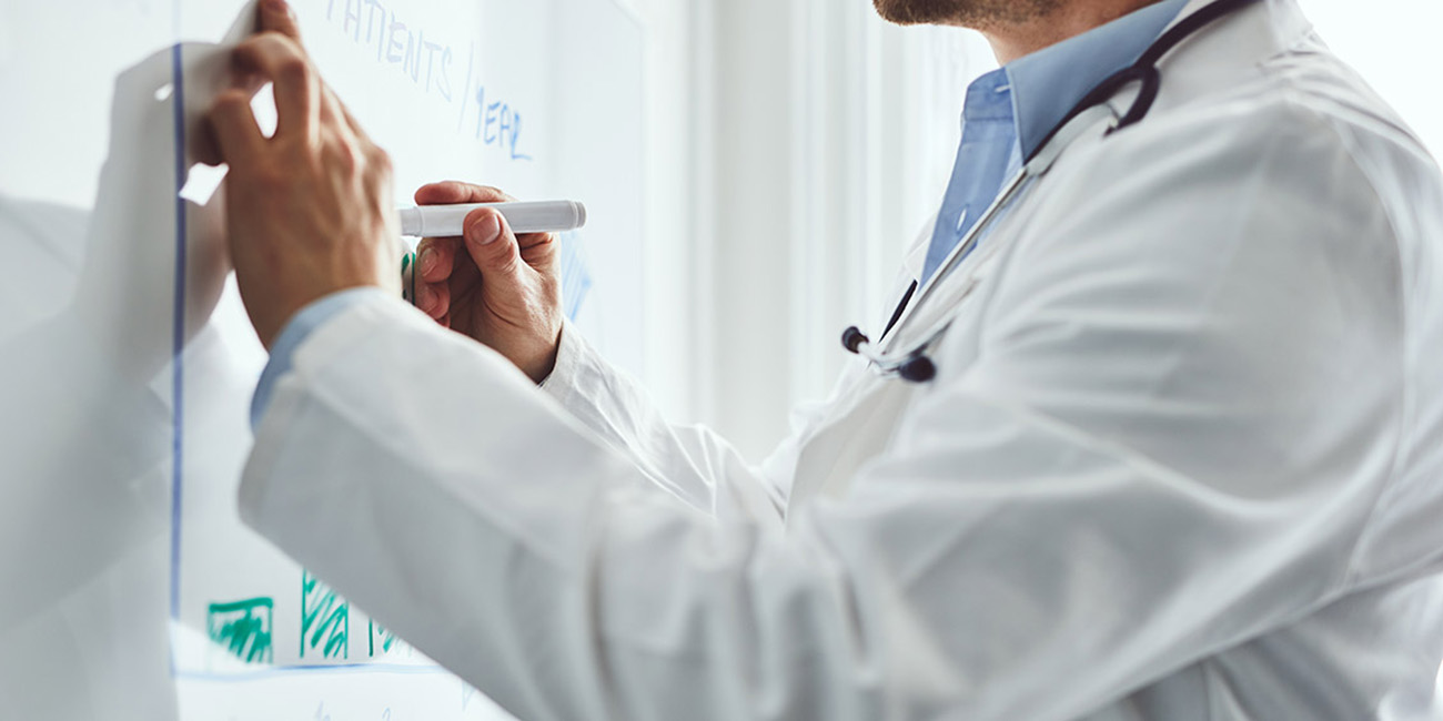 health care provider drawing bar graphs on dry erase board