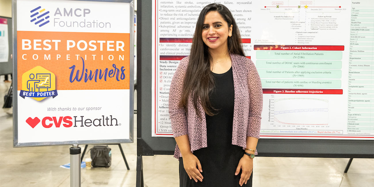 Fatima standing at poster next to AMCP winners sign