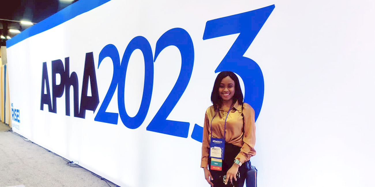 Olateju next to APhA signage