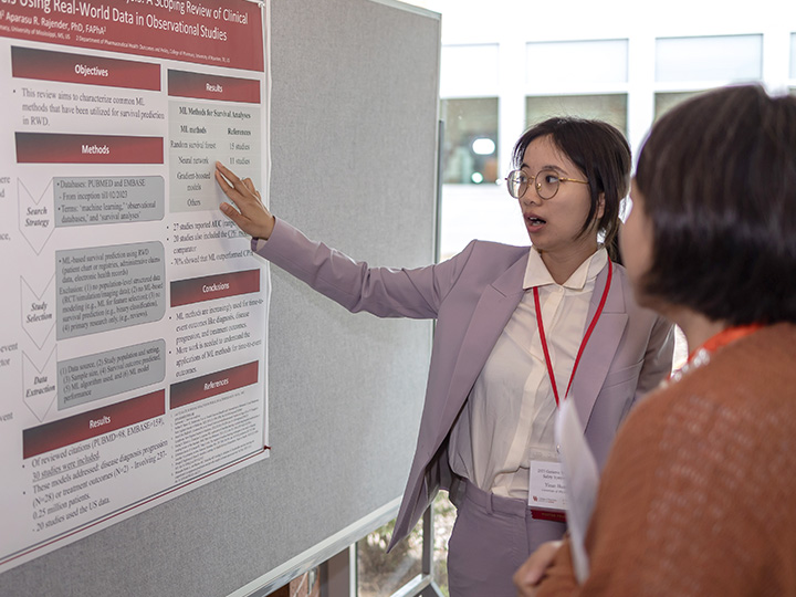 Wang talking to attendee at poster