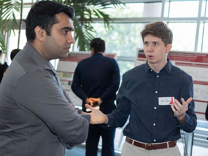 Hudson talking with attendee at poster