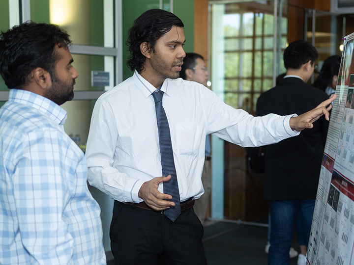 Datta talking with attendee at poster