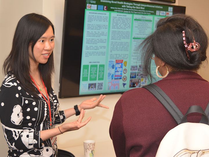 Tat talking with attendee about poster at monitor