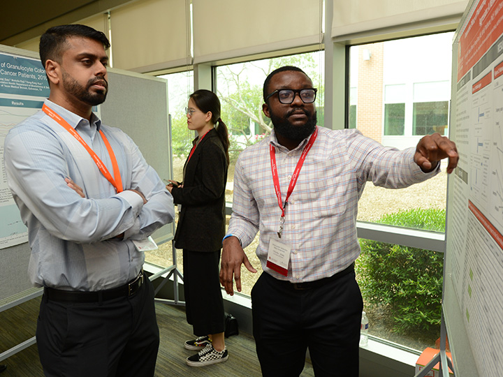 student gesturing to poster during presentation