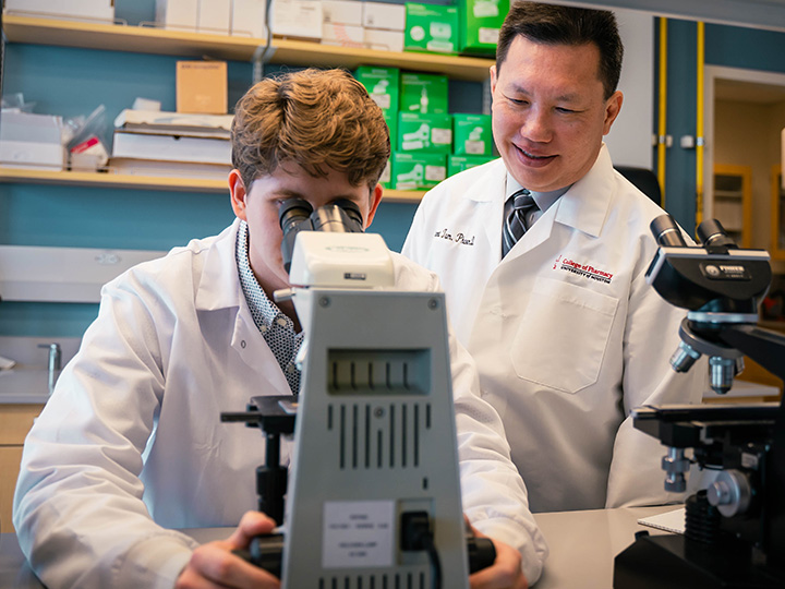 Tam and Hudson at microscope in lab