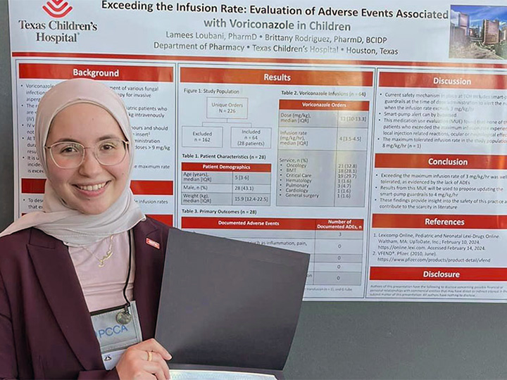 Loubani holds her honorable mention certificate in front of her poster