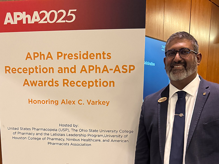 Varkey stands next to sign for President's Reception