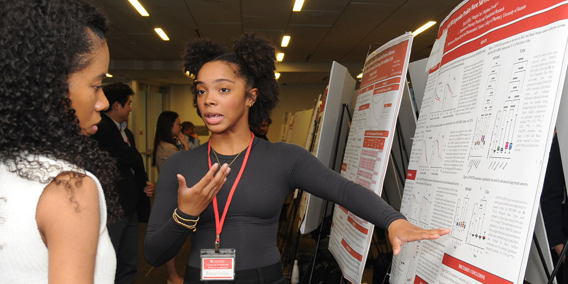 student researcher at poster discussing her project with attendee