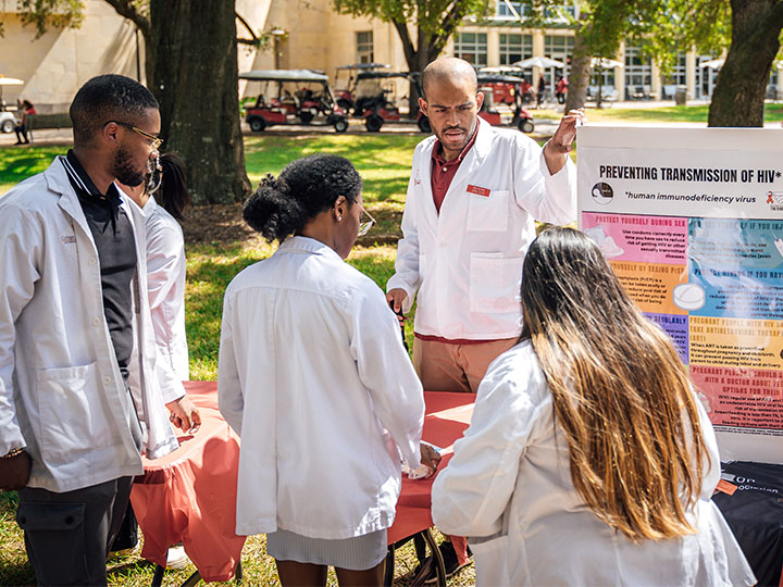 Kappa Psi members at health poster during outdoor health fair
