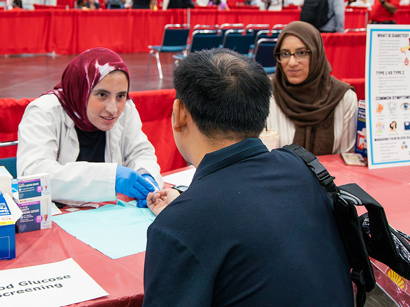 student and preceptor with blood glucose screening patient