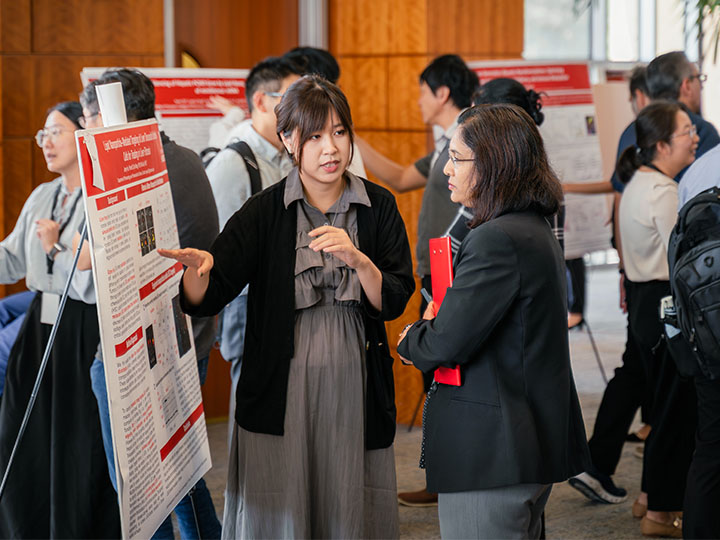 Hu discussing poster project with attendee