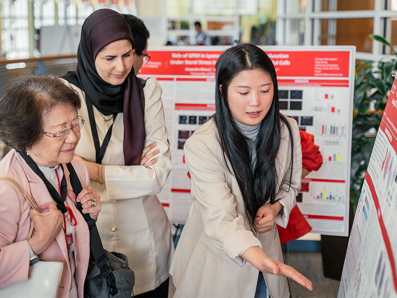 symposium presenter explaining poster to attendees