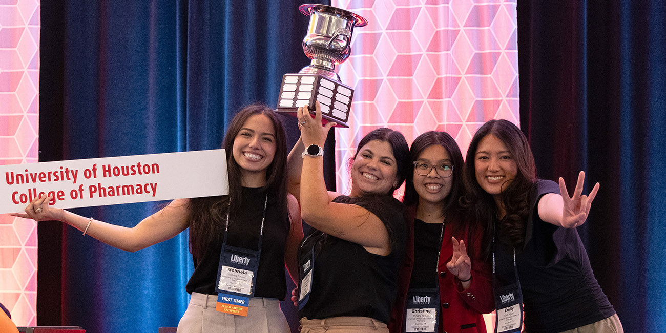 pharmacy students holding sign and trophy