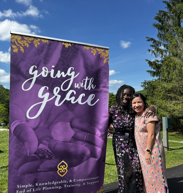 Two women embracing next to a purple banner