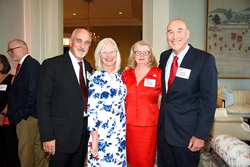 A group of two men and women stand together smiling in ballroom lobby.
