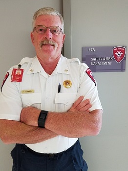 A man with a mustache wearing glasses standing by a door