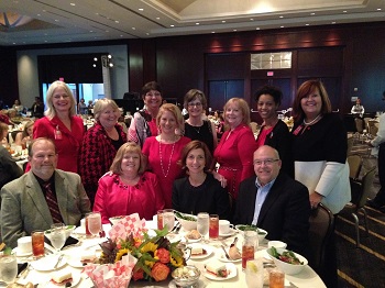 A group of poeple sit and stand around a banquet table.