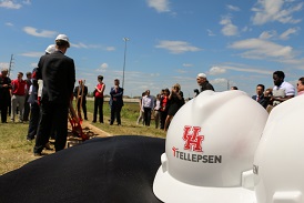 White hardhats on a table with a group of people gathered in the background