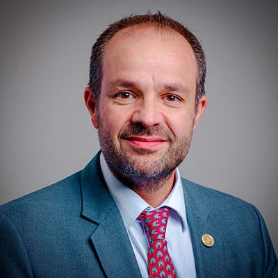 Portrait of a Hispanic man with a short faded beard in a blue business suit