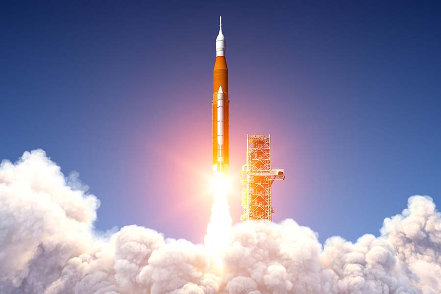 The NASA Space Launch System lifting off from its launch pad. A large plume of exhaust fills the bottom portion of the picture.