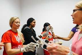 Nursing students wearing heavy gloves are being handed special glasses