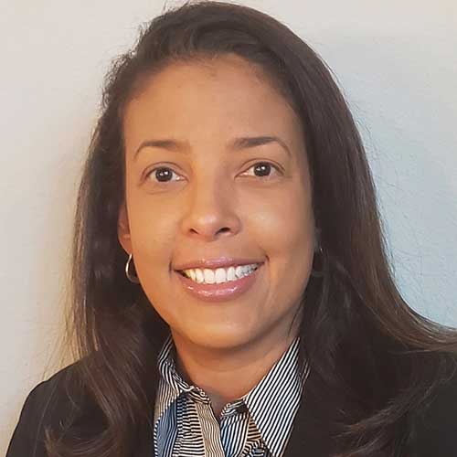 Portrait of a Black woman smiling with long straight hair wearing a black business jacket and a black and white striped shirt