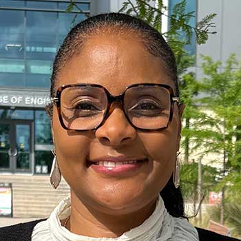 Portrait of a Hispanic woman outdoors with glasses and her hair tied back.