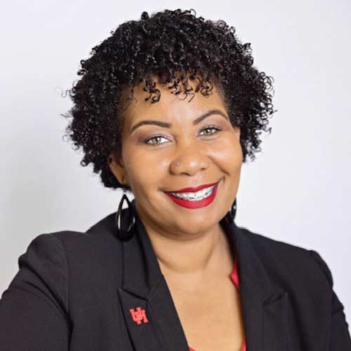 Portrait of a black woman smiling with dark ear length hair wearing a black suit