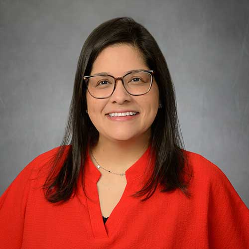 Portrait of a Hispanic woman smiling with dark long hair wearing a red blouse
