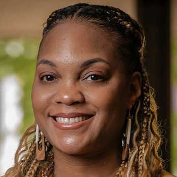 Portrait of a Black woman smiling with braided shoulder-length hair with streaks of blonde