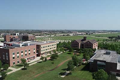 Aerial photograph of a small university campus with homes and businesses in the background