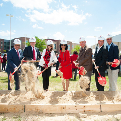 A group of people in suits shoveling sand